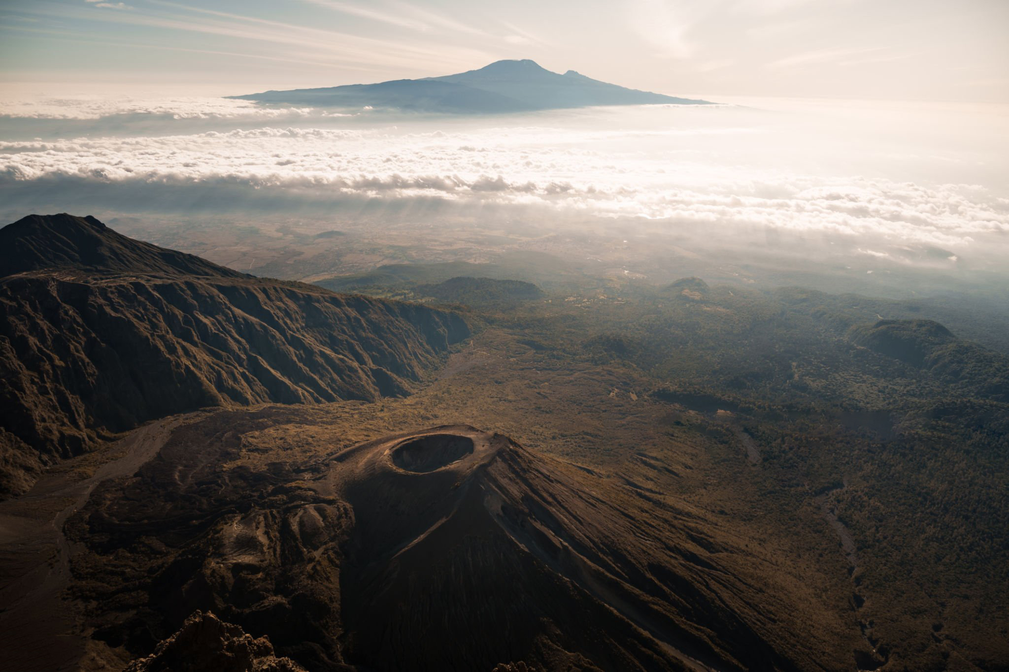 Stunning aerial view of mount meru's volcanic crater and slopes, with kilimanjaro rising majestically in the distance, during sunrise climb in tanzania, africa